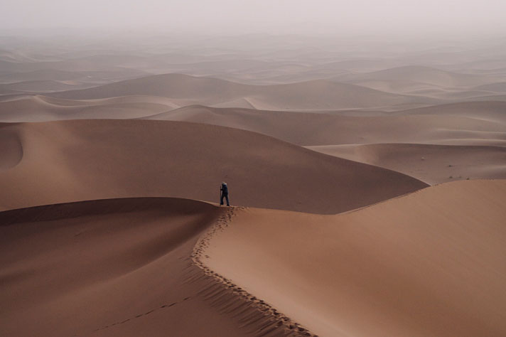 A man standing on a sand dune in a sandy desert