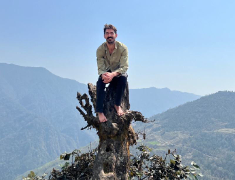 Ben in the mountains sitting on a tree stump